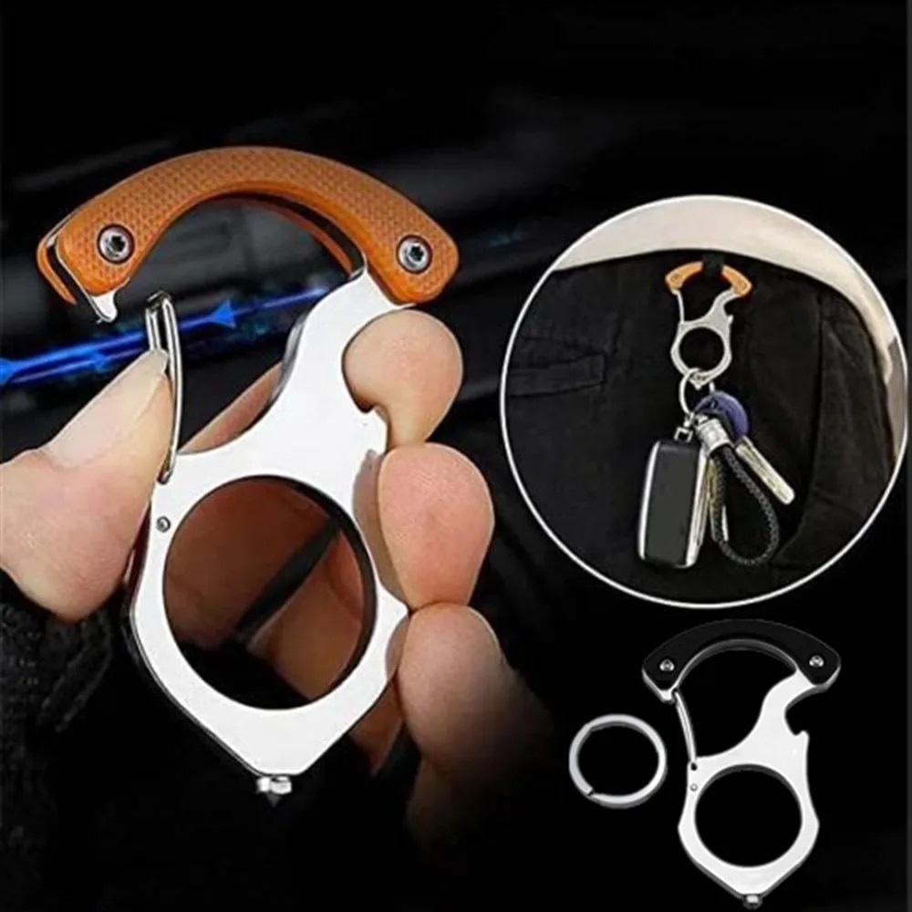 Metalen sleutelhanger met oranje handvat in de hand, met inzet van de haak aan een broekzak met autosleutels en een los sleutelringetje. 2