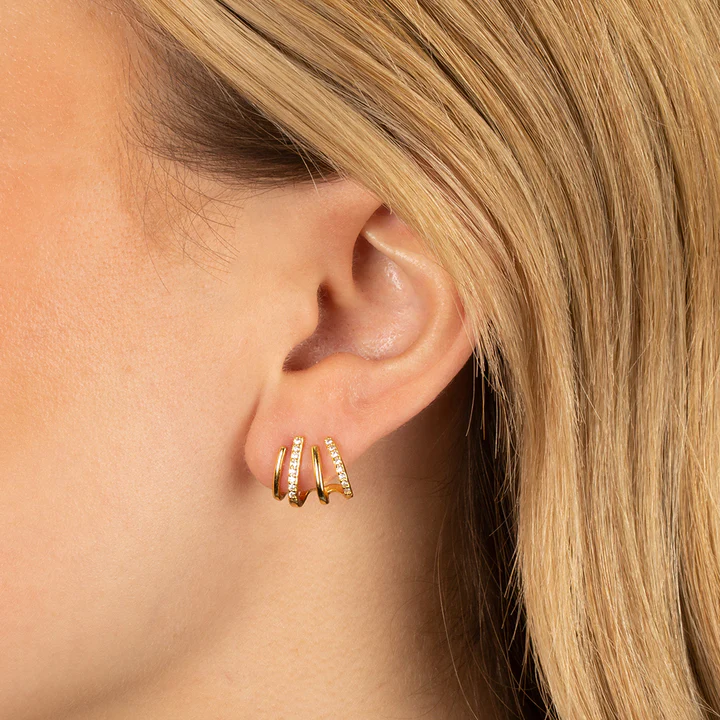 Close-up van een oor met blond haar met een gouden oorbel met vier klemmen 4