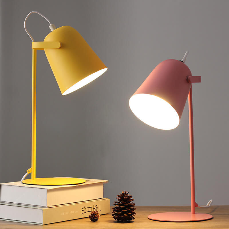 Gele en roze bureaulamp naast elkaar, brandend op een houten tafel met boeken en dennenappels. 5