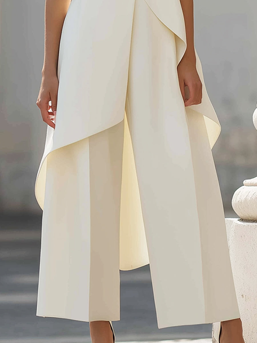 Detail van de crèmewitte broek met wijde pijpen, bandplooien en de golvende onderrand van de asymmetrische top. 12