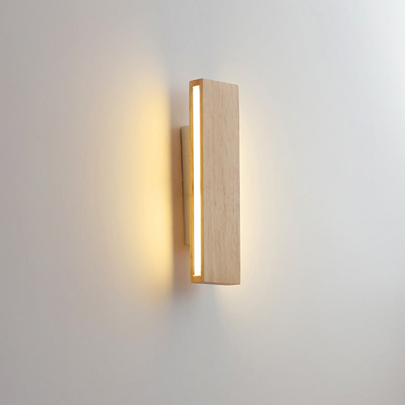Verticale houten wandlamp met een smalle lichtstrip aan de zijkant die warm licht over de muur werpt. 10