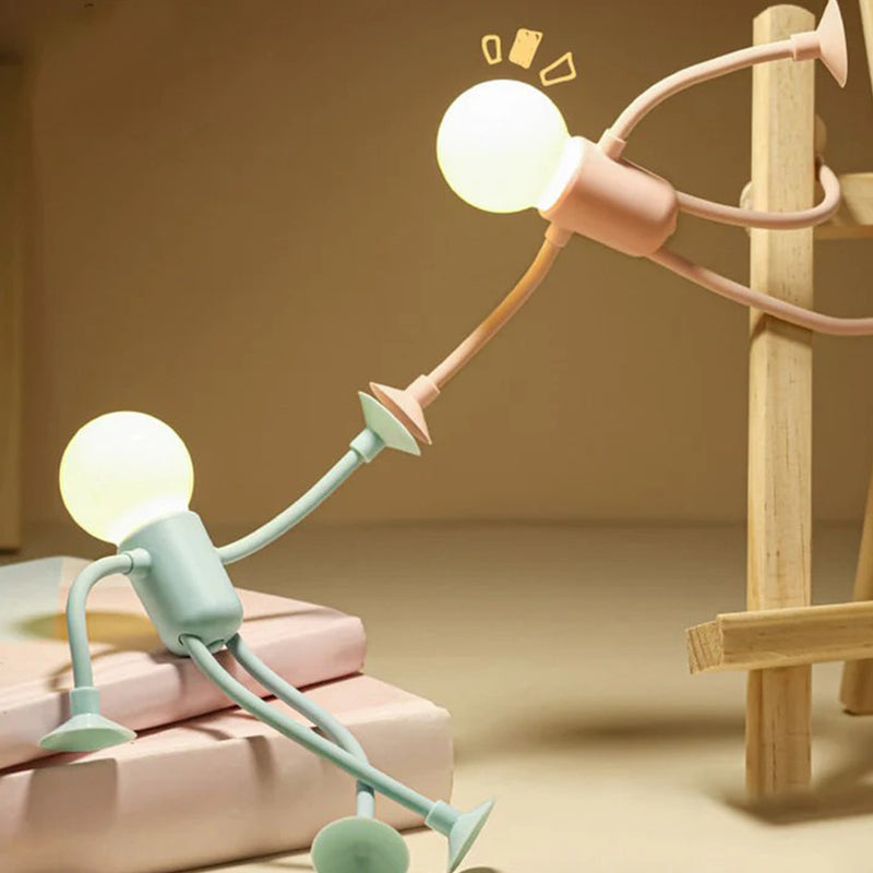 Groen en roze mannetjeslampje bij elkaar: het groene zit op boeken en reikt omhoog, het roze hangt aan een houten ladder. 6