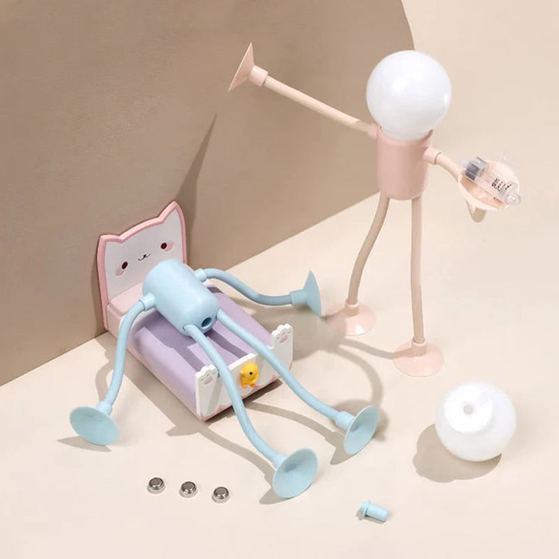 Roze mannetjeslampje houdt een batterijtje vast naast een blauw exemplaar op een kattenbedje, met losse lampbol en drie knoopcelbatterijen ernaast. 13