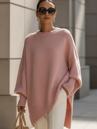 Roze gebreide poncho gedragen met witte broek, zonnebril en beige handtas 11