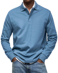 Man draagt het poloshirt met lange mouwen in een middenblauwe kleur, over een gestreept overhemd en met een spijkerbroek. 2
