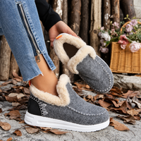 Grijze instapsneakers met pluchen voering; het model houdt één schoen omhoog zodat de zachte binnenkant zichtbaar is. 5