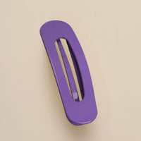 Matte paarse haarclip met ovale opening, schuin van boven gefotografeerd op een beige achtergrond 11