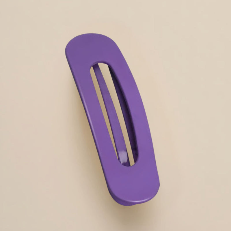 Matte paarse haarclip met ovale opening, schuin van boven gefotografeerd op een beige achtergrond 11