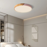 Ronde plafondlamp met roze rand en houten deel boven een slaapkamer met wit beddengoed 5