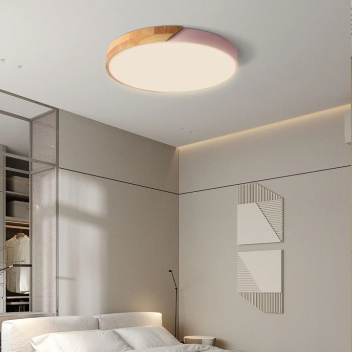 Ronde plafondlamp met roze rand en houten deel boven een slaapkamer met wit beddengoed 5