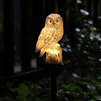 Close-up van de witte uil met gele ogen, 's nachts verlicht in warm licht vanuit de boomstronk onder hem. 6
