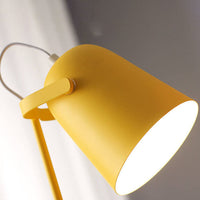 Close-up van de gele lampenkap van onderaf, met het verstelbare scharnier en het witte licht binnenin. 2