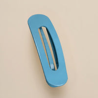 Matte hemelsblauwe haarclip met ovale opening, schuin van boven gefotografeerd op een beige achtergrond 14