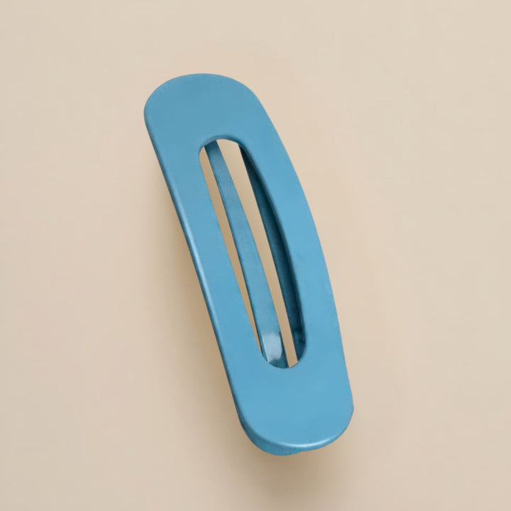 Matte hemelsblauwe haarclip met ovale opening, schuin van boven gefotografeerd op een beige achtergrond 14