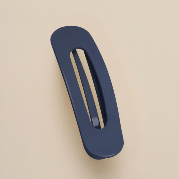 Matte donkerblauwe haarclip met ovale opening, schuin van boven gefotografeerd op een beige achtergrond 15