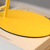 Close-up van de ronde gele voet met zwarte rand, staand op een boek. 4