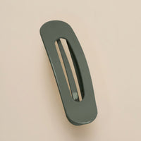 Matte donkergroene haarclip met ovale opening, schuin van boven gefotografeerd op een beige achtergrond 16