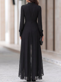 Achterkant van de zwarte set met ritssluiting in het midden van de rug, knoopjes aan de manchetten en een wijd uitlopende doorschijnende chiffon laag. 5