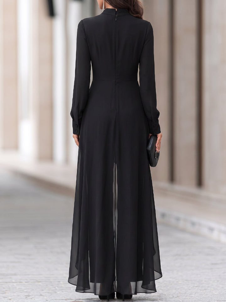 Achterkant van de zwarte set met ritssluiting in het midden van de rug, knoopjes aan de manchetten en een wijd uitlopende doorschijnende chiffon laag. 5