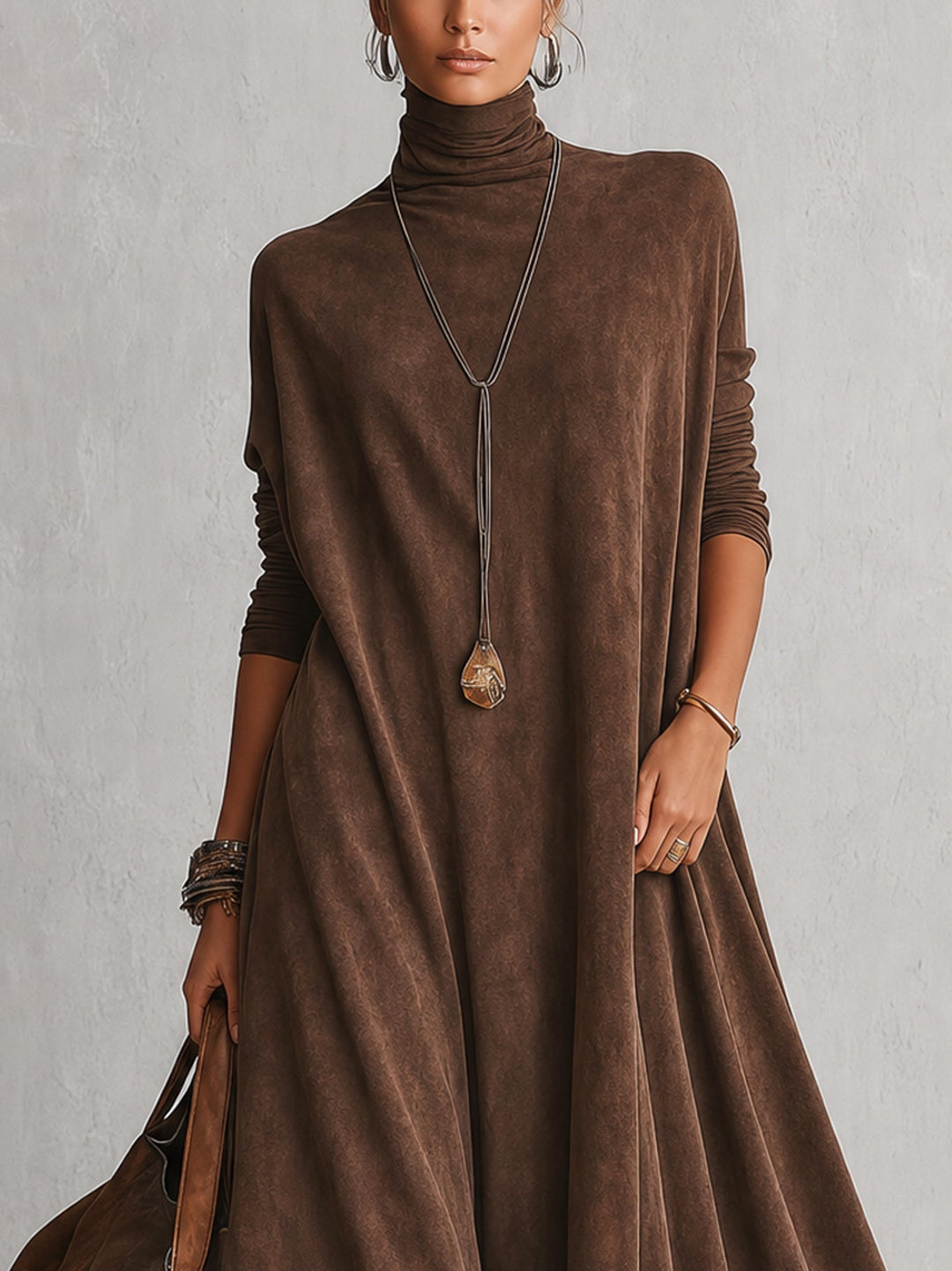 Close-up van het bovenlijf: bruine jurk met col en lange mouwen, model met lange ketting 2