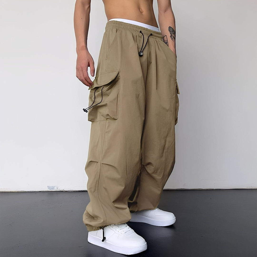 Model draagt de ruime cargobroek in beige met zijzakken, trekkoord en witte sneakers, schuin van voren 1