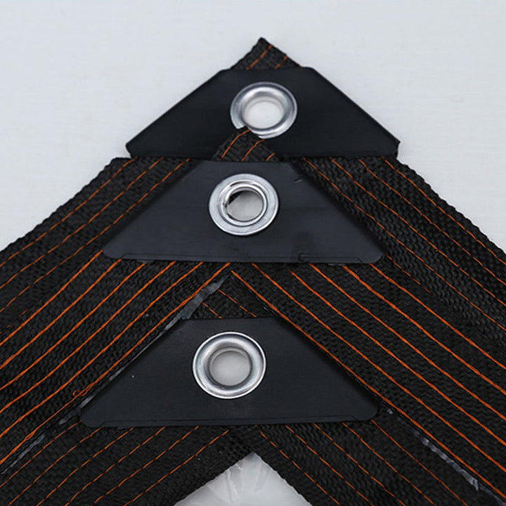 Detail van drie hoekversterkingen met metalen oogjes op de zwarte, geweven zeilrand met oranje stiknaden. 5