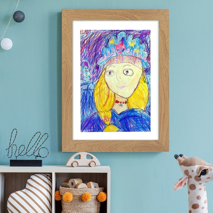 Houtkleurig frame aan een blauwe muur met een kleurpotloodportret van een meisje met kroon, boven een kastje met speelgoed. 15