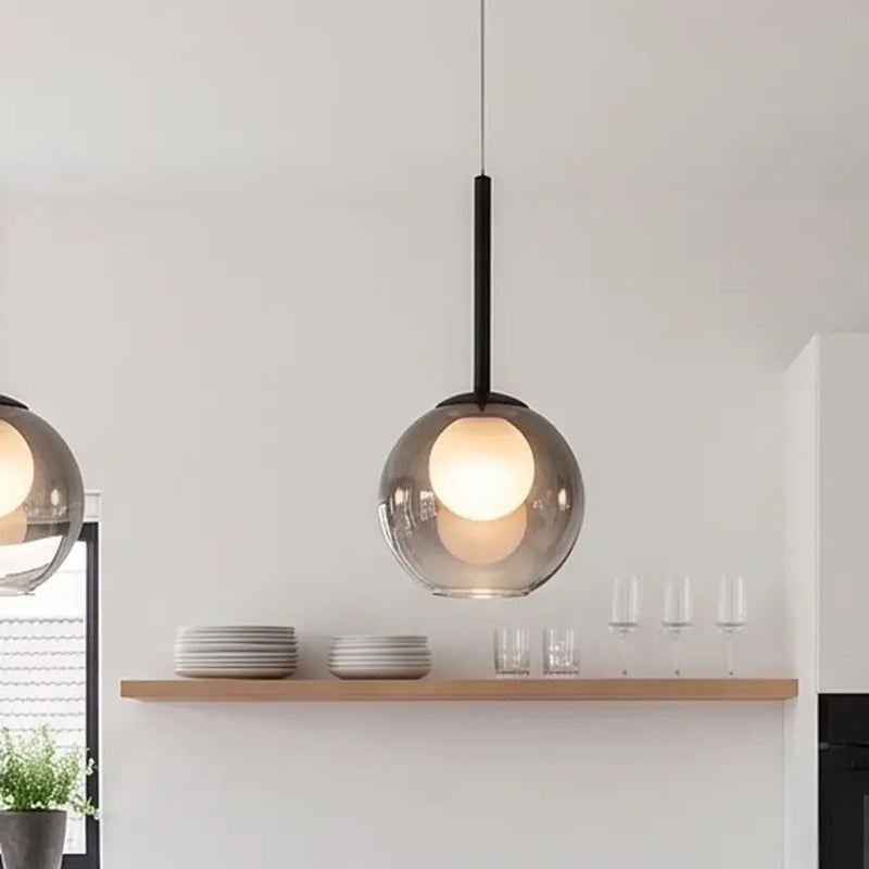 Close-up van een rookgrijze globelamp met zwarte steel boven een houten schap met borden en glazen 11