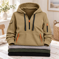 Zandkleurige hoodie met halve rits, zwarte koorden en oranje ritsen, bovenop gevouwen truien 4