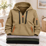 Zandkleurige hoodie met halve rits, zwarte koorden en oranje ritsen, bovenop gevouwen truien 4