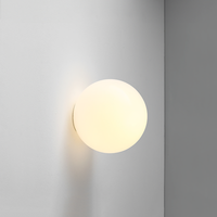 Close-up van een lichtgevende opaalglazen bol tegen een grijze muur, met warme gloed 16
