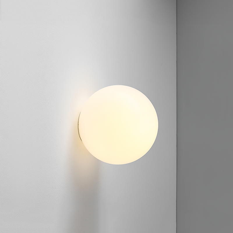 Close-up van een lichtgevende opaalglazen bol tegen een grijze muur, met warme gloed 16