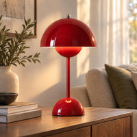 Glanzend rode versie van de lamp met warm licht, op een houten dressoir naast boeken 7