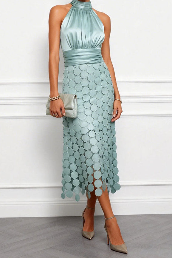 Model draagt de halsjurk in zachte mintgroene tint met bijpassende clutch en beige pumps, rok met ronde applicaties. 2