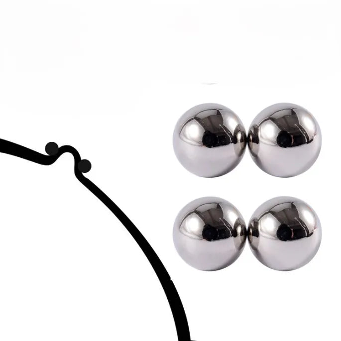 Productfoto op een witte achtergrond van twee paar glanzende zilverkleurige magneetbolletjes, naast een zwarte getekende lijn met twee kleine bolletjes. 6