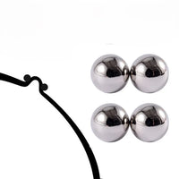 Productfoto op een witte achtergrond van twee paar glanzende zilverkleurige magneetbolletjes, naast een zwarte getekende lijn met twee kleine bolletjes. 6