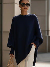 Marineblauwe gebreide poncho gedragen met witte broek, zonnebril en beige handtas 9