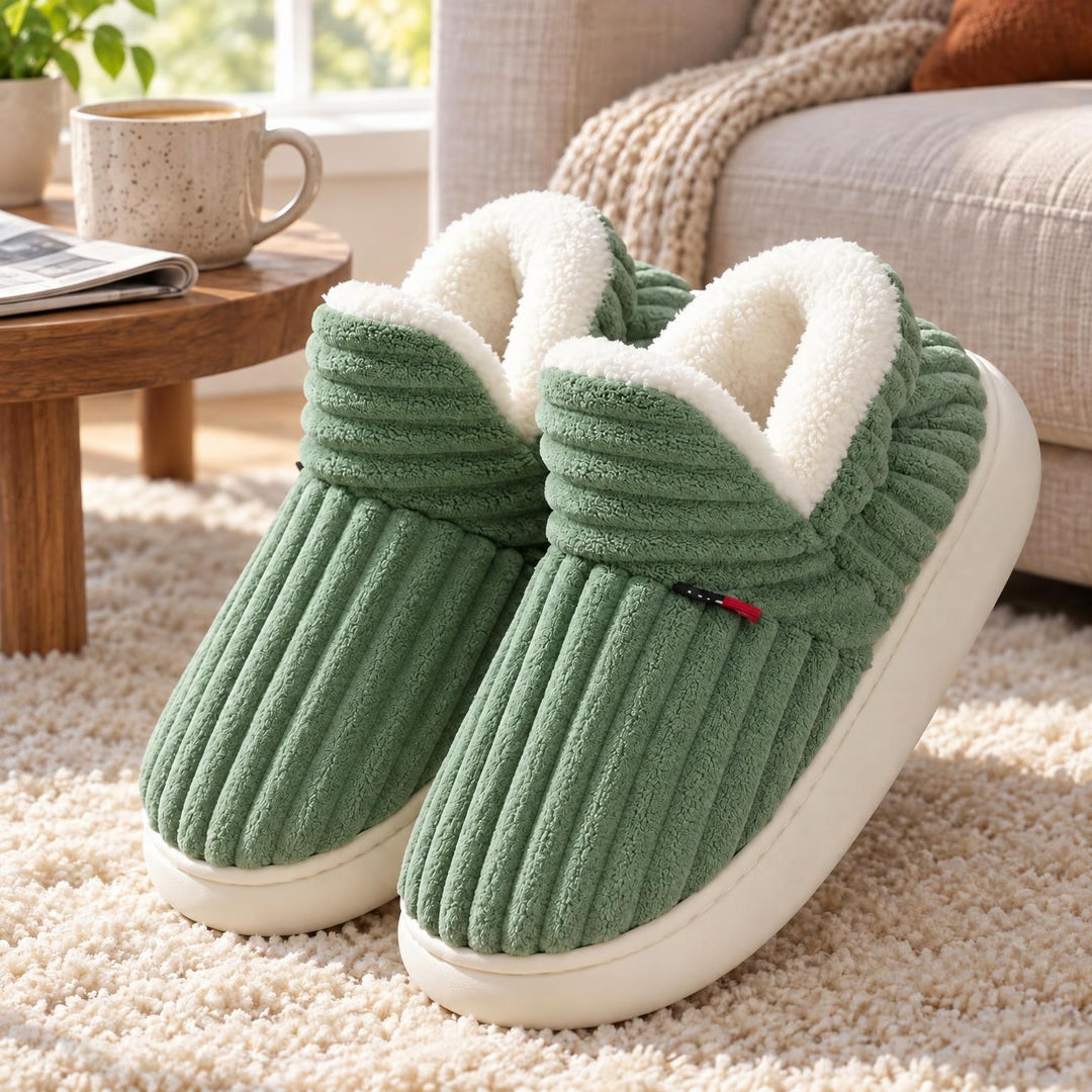 Groene geribbelde pantoffels met witte pluchevoering en dikke witte zool op een zacht vloerkleed bij de bank 5