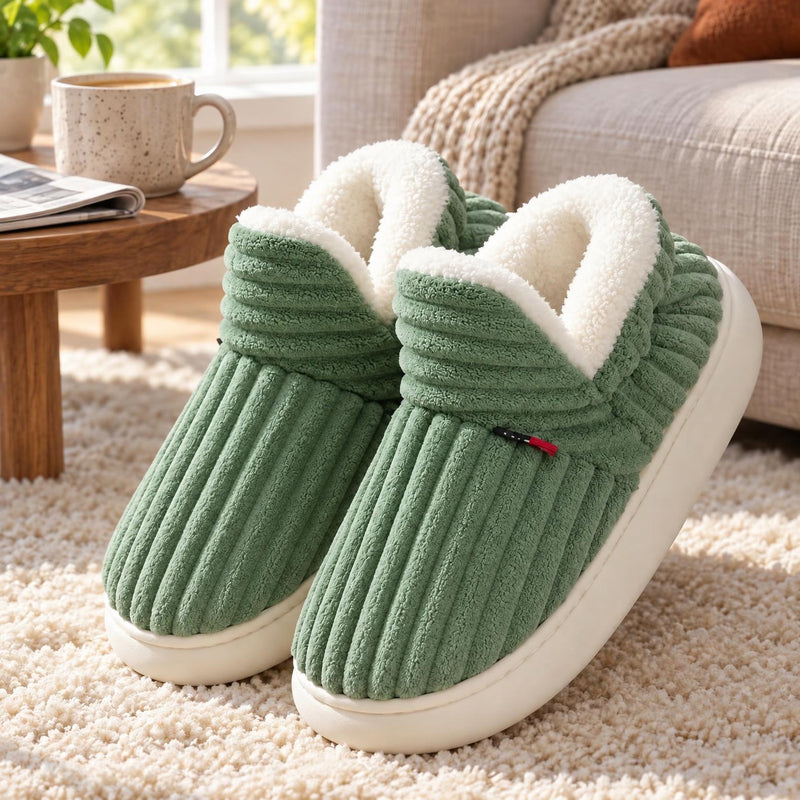 Groene geribbelde pantoffels met witte pluchevoering en dikke witte zool op een zacht vloerkleed bij de bank 5