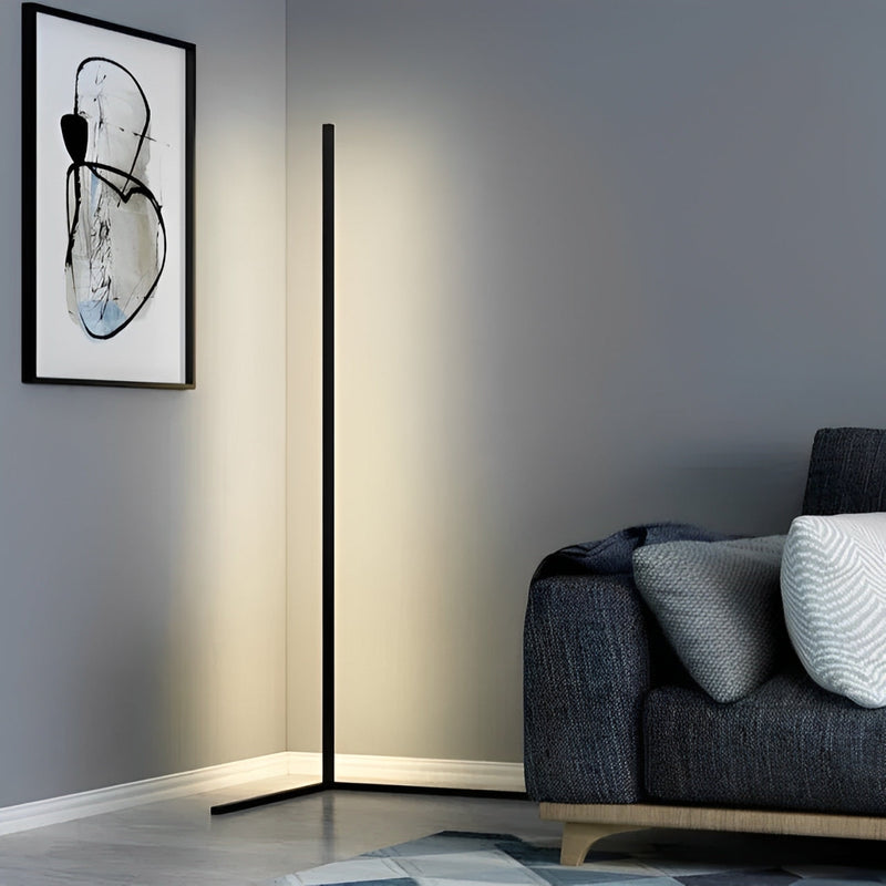 Zwarte staande ledlamp in een hoek van een woonkamer naast een donkerblauwe bank en een schilderij 5