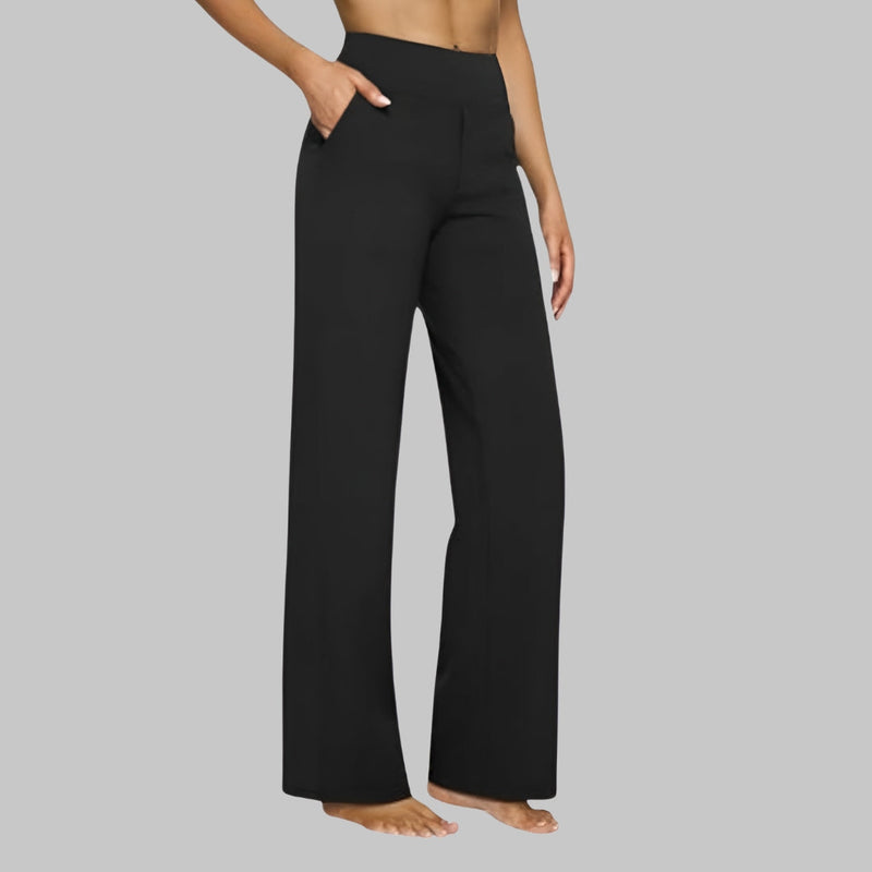 Model in zwarte broek met hoge taille en rechte pijpen, zijaanzicht met een hand in de zijzak. 9