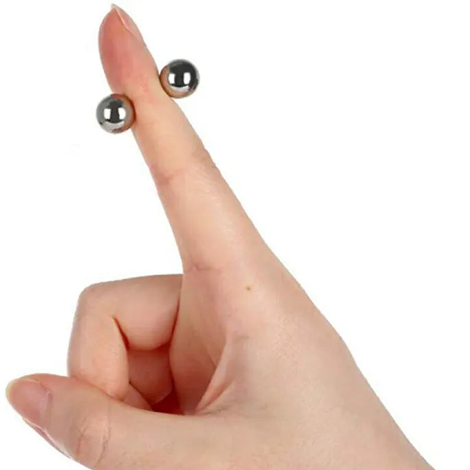 Twee kleine metalen bolletjes klemmen aan weerszijden van een opgestoken wijsvinger en laten de magnetische hechting zien. 8
