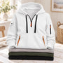 Witte hoodie met zwarte koorden en oranje details, bovenop een stapel gevouwen truien 8