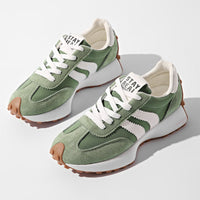 Paar groene suède sneakers met witte strepen en gomzool, van bovenaf op een witte ondergrond 1