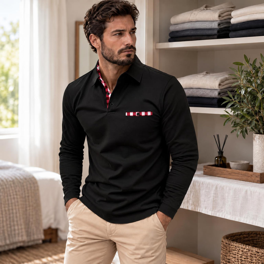 Model in zwarte polo met geruite kraagbinnenkant en zakje, handen in de zakken van een beige broek 2