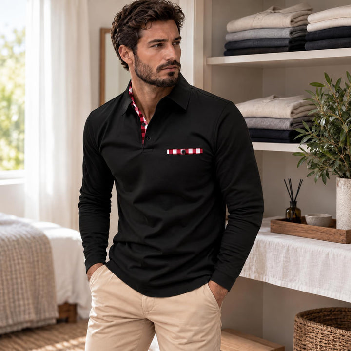 Model in zwarte polo met geruite kraagbinnenkant en zakje, handen in de zakken van een beige broek 2