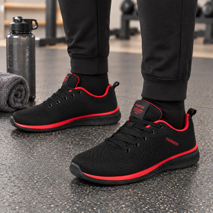 Zwarte gebreide sneakers met rode accenten langs de zool en de binnenrand, in de sportschool gedragen 3