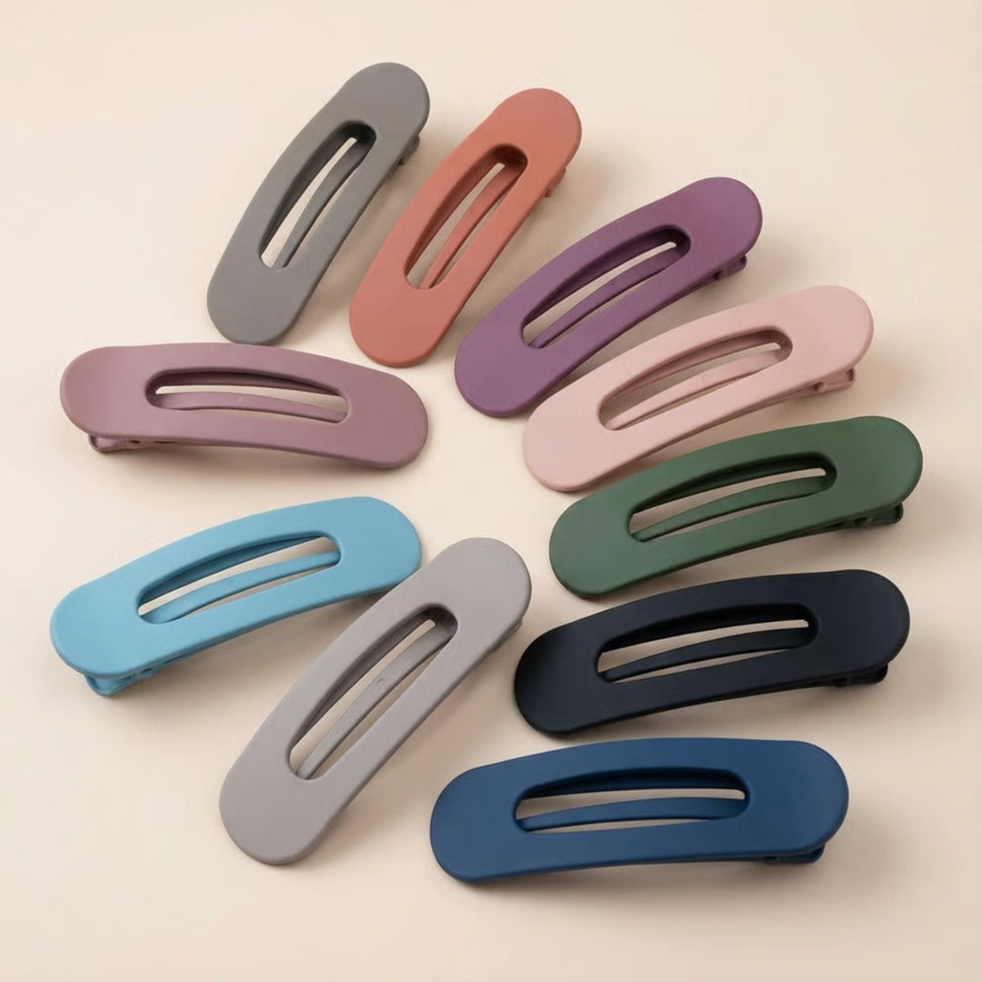 Tien matte platte haarclips in verschillende kleuren, in een cirkel gelegd op een lichte ondergrond 1