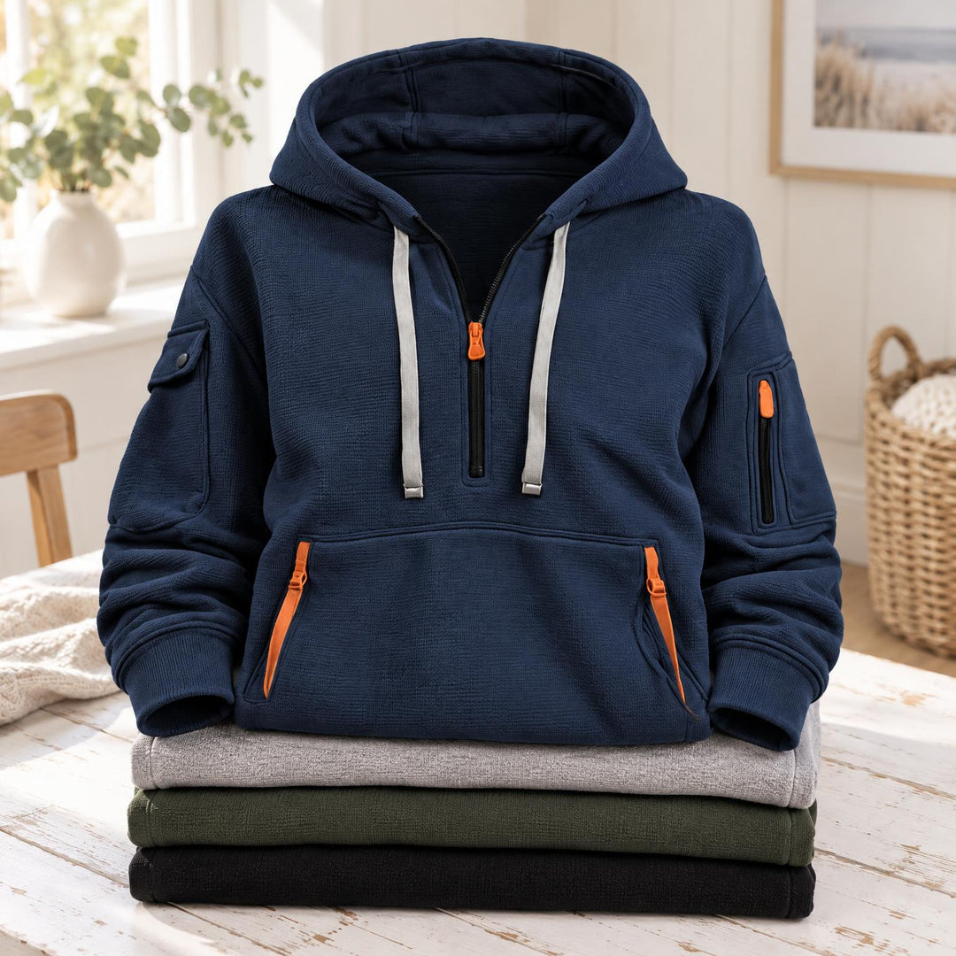 Marineblauwe hoodie met halve rits en kangoeroezak, bovenop een stapel gevouwen truien 2