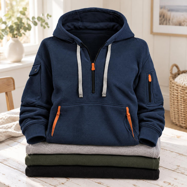 Marineblauwe hoodie met halve rits en kangoeroezak, bovenop een stapel gevouwen truien 2